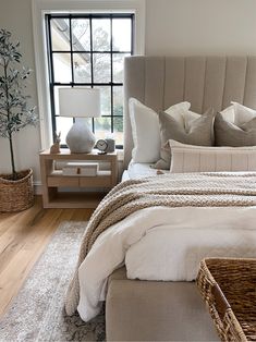 a bed sitting next to a window on top of a wooden floor in a bedroom