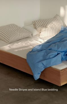 an unmade bed with blue sheets and striped pillow cases on it's sides