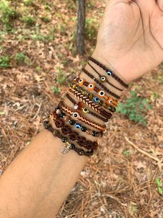 a hand is holding several bracelets with evil eyes on them in the woods and grass