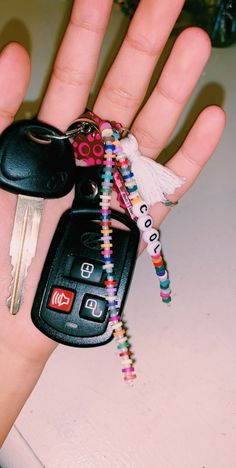 a hand holding a car key chain with keys attached to it's thumb,