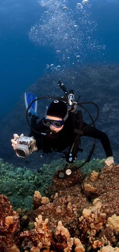 a scuba diver in the water with his camera and equipment on top of some corals