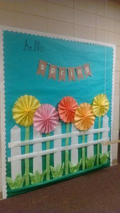 a bulletin board decorated with paper flowers and the words spring written on it in front of a fence