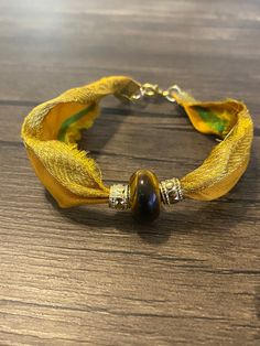 "I love creating this bracelet with my favorite free trade Sari Silks.   This beautiful sari silk is in golden yellow, with gold tone threads, measures appx 7\" in length from end to end. The tiger's eye stone is accented with two gold tone metal barrel beads.  The width measures appx 1\".  If you are looking for a longer bracelet, I can add an extender chain.  If you would like the bracelet cut to size, please let me know and I can work with you.  This bracelet is a beautiful accent to any outf Sari Silk Bracelet, Grunge Bracelets, Sari Silk Jewelry, Bracelets Outfit, Hippie Bracelet, Metal Barrel, Silk Bracelet, Free Trade, Silk Jewelry