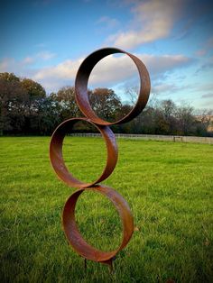 a metal sculpture in the middle of a grassy field