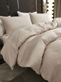 an unmade bed in a hotel room with white sheets and pillows on the headboard