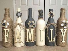 four wine bottles are decorated with flowers and the word family is spelled out in front of them