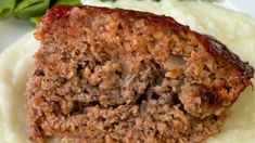 meatloaf and mashed potatoes on a plate with green leaves in the background