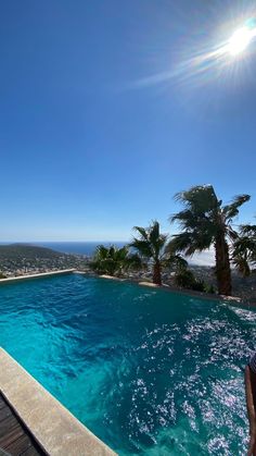 an empty swimming pool with blue water and palm trees in the background on a sunny day