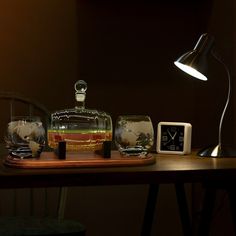 a wooden table topped with two glass vases and a clock next to a lamp