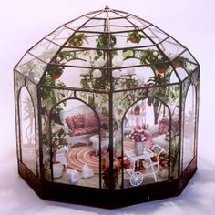 a glass gazebo with flowers and furniture in it on a white tablecloth background