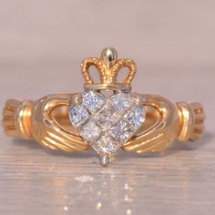 a gold ring with a heart shaped diamond in the middle and two smaller hearts on each side