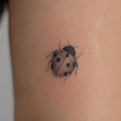 a ladybug tattoo on the back of a woman's right thigh,