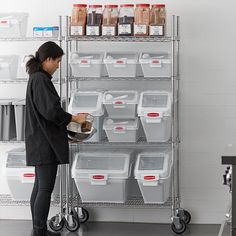 a woman standing in front of a shelf filled with containers and bins holding food