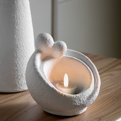 a white candle holder sitting on top of a wooden table