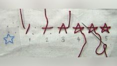 some red thread on top of a white piece of paper with blue stars and numbers