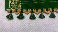 green and gold tassels are hanging from a white cloth