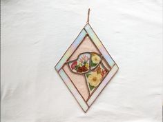 a stained glass ornament hanging on a white wall with flowers in the center