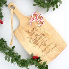 a personalized cutting board with candy canes on it and greenery around it