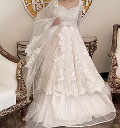 a woman in a wedding dress standing next to a chair