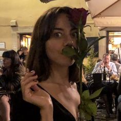 a woman holding a rose up to her mouth