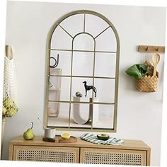 a mirror sitting on top of a wooden cabinet next to a vase and fruit bowl