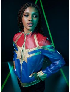 a woman with braids wearing a blue and red leather jacket is posing for the camera