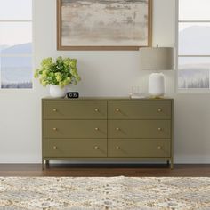 a green dresser with two vases and a painting on the wall above it in a living room