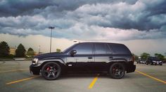 a black suv parked in a parking lot under a cloudy sky