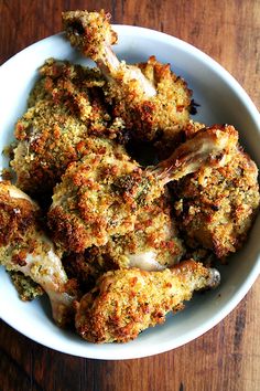 a white bowl filled with cooked chicken on top of a wooden table