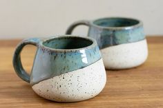 two blue and white mugs sitting on top of a wooden table next to each other