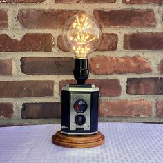 an old fashioned light bulb sitting on top of a wooden table next to a brick wall