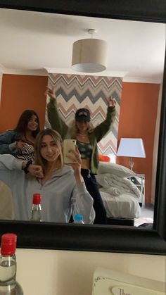 three women are taking a selfie in the mirror while one woman is holding up her phone