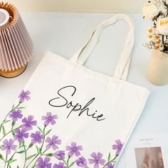 a purple flowered tote bag sitting on top of a table next to photos