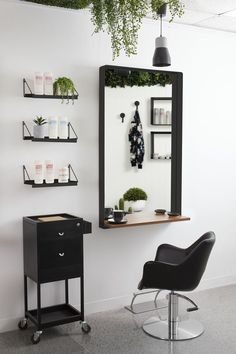 a chair sitting in front of a mirror next to a shelf with plants on it