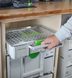 a person is opening the bottom drawer of a storage unit