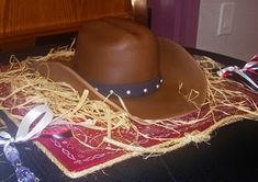 a brown cowboy hat sitting on top of a table next to a red and white ribbon