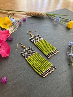 two pairs of beaded earrings sitting on top of a piece of cloth next to flowers