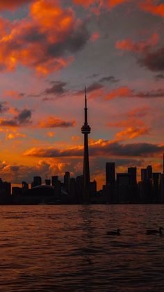 the sky is red and orange as the sun sets in front of a cityscape