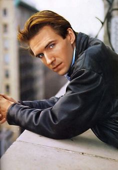 a man in a leather jacket leaning on a ledge