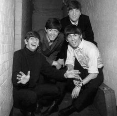 the beatles posing for a black and white photo in an alleyway with brick walls