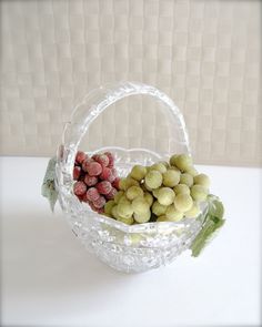 a glass basket filled with green and red candy candies on top of a white table