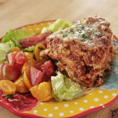 a plate topped with lasagna and salad on top of a yellow and red plate