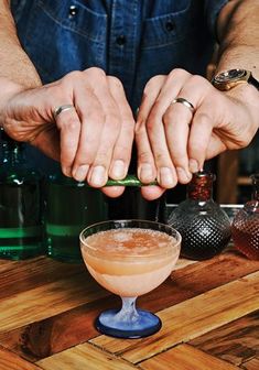 the bartender is making an alcoholic cocktail in his home bar with two hands on the table