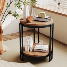 a round wooden table with books and vases on it next to a potted plant