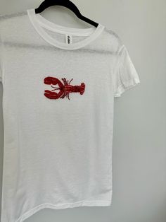 Hand embroidered lobster shirt, 8 hours of work each bead is sewn by hand. Truly a labor of love. All done by hand with glass bead details, expect variations since this is a custom piece. Soft stretchy tshirt material.  Please expect 5-7 days to be completed and shipped. Rush orders can be requested for an extra fee, please message me to inquire.  -Sizes are US Women Made with love always <3 *Hand wash ideally or machine was on delicate inside out in a garment bag. Hang to dry. Fitted Casual T-shirt With Custom Embroidery, Embellished Fitted Cotton T-shirt, Fitted Cotton Embellished T-shirt, Fitted Tops With Custom Embroidery And Short Sleeves, Fitted Short Sleeve Tops With Custom Embroidery, Red Short Sleeve Tops With Custom Embroidery, Beaded Lobster, With Love Always, Lobster Shirt