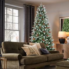 a living room with a christmas tree and couches in front of the window,