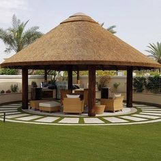 a gazebo with chairs and tables in the middle of a lawn area next to palm trees