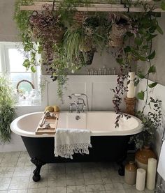 a bathtub filled with lots of plants next to a window in a white tiled bathroom