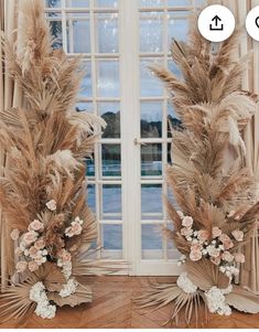 two tall vases with flowers and feathers in front of a window, both decorated by the same person