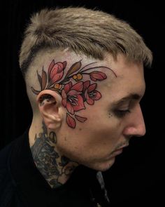 a man with tattoos on his face and behind the ear is an image of flowers